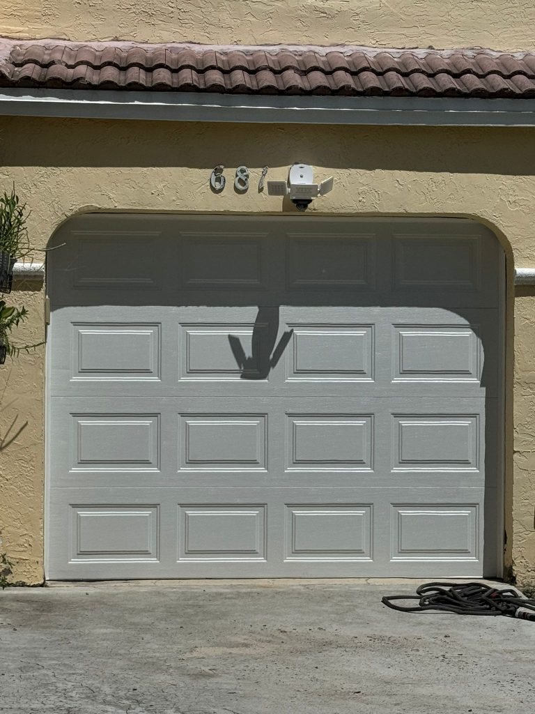 A white garage door with a decorative arch and the house number 681 above it. There is a security light above the numbers, a coiled garden hose on the ground to the right, and "Job 4621" noted by Stephen Solari on the light yellow exterior wall.