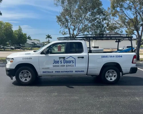 A white pickup truck with "Joe’s Doors Garage Door Services" signage is parked in a lot, advertising garage door repair and installation. The ladder rack and contact info highlight their expert garage door services. Trees line the background.